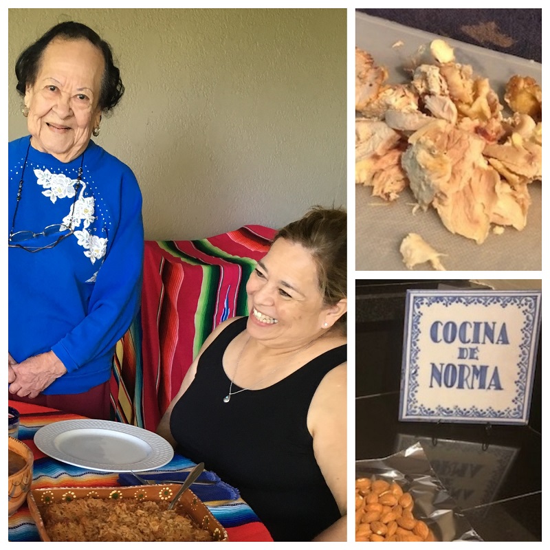 A younger woman and and older woman enjoy mole. A sign reads "Cocina de Norma."
