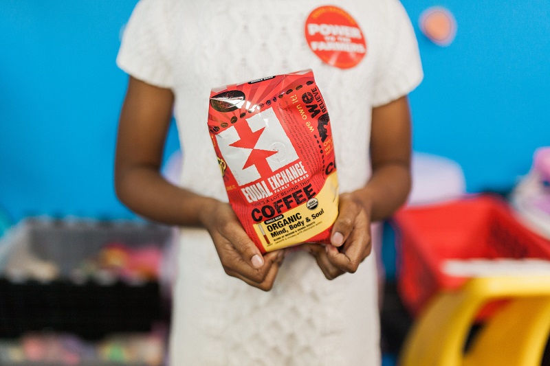 A little girl holds a bag of Equal Exchange fair trade coffee.