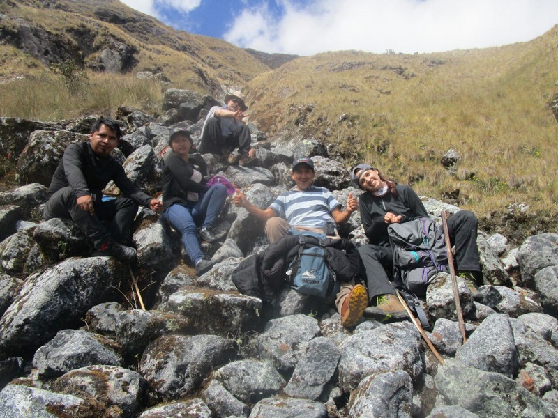 Five hikers relax on a stony outcropping, taking a break.