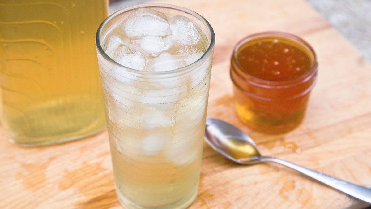 Glass of iced green tea next next to honey pot