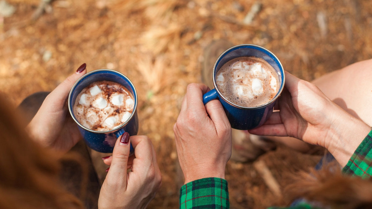 Holding mugs of autumn spice hot cocoa outdoors