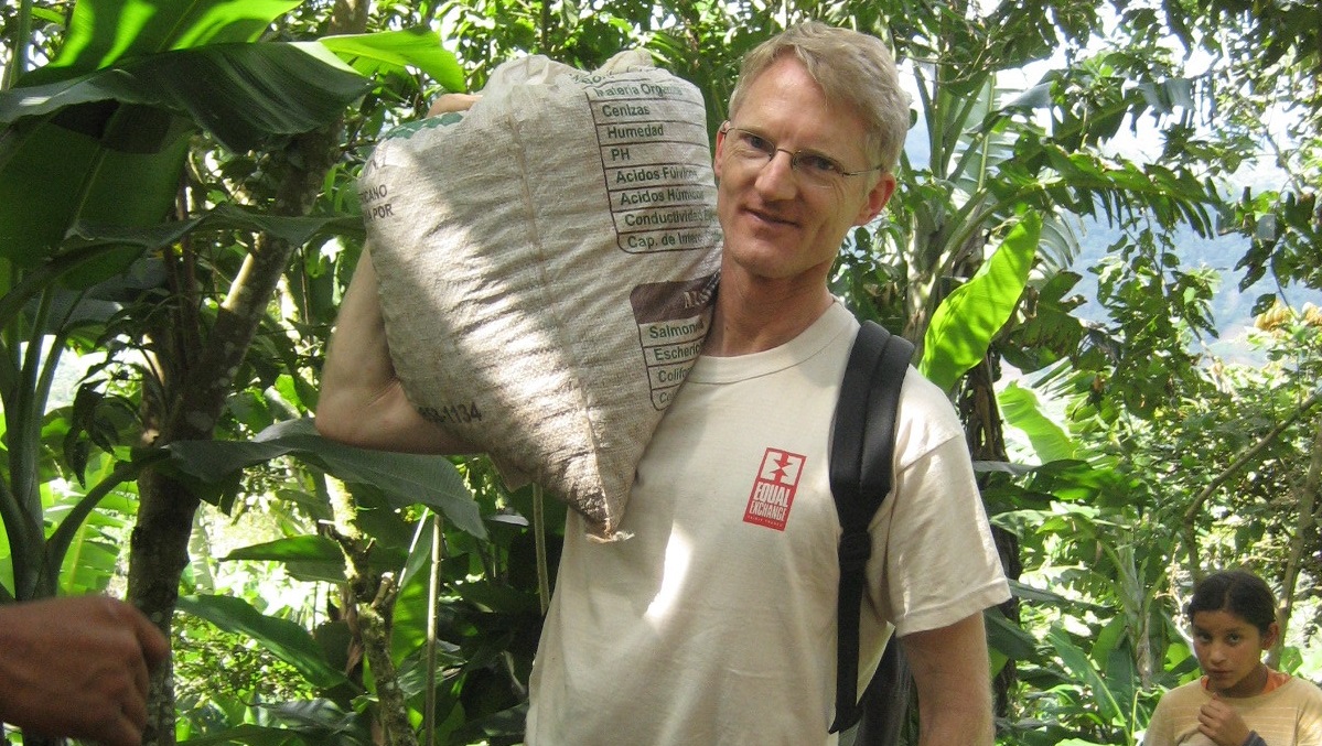 A man hefts a bag of coffee over one shoulder.