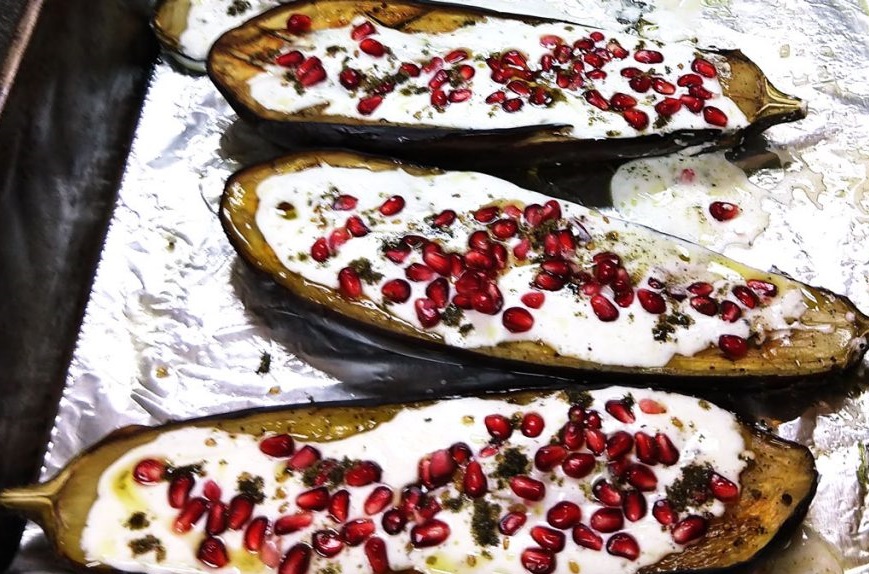 Roasted eggplants topped with creamy sauce and bright pomegranate seeds