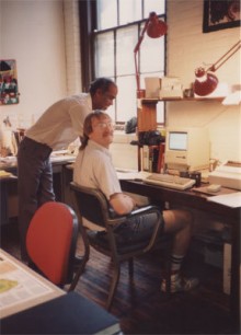 A man with a dated haircut sits at a desk