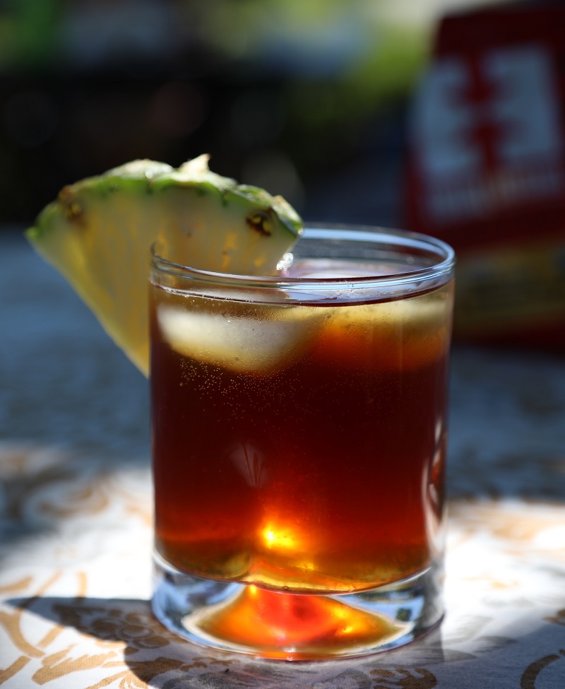 A cold brew cocktail with a wedge of pineapple