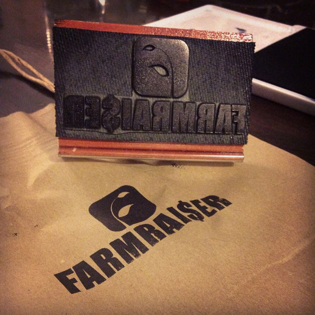 Image shows a rubber stamp of the FarmRaiser logo on a paper fundraising product distribution bag.