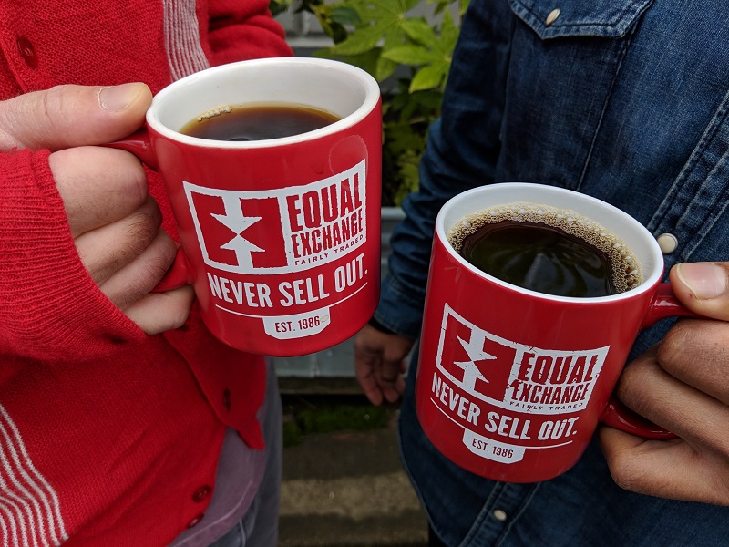 Two mugs that read "never sell out" clink a cheers
