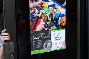 poster on a door that says "we support small farmers" and "Sale today"