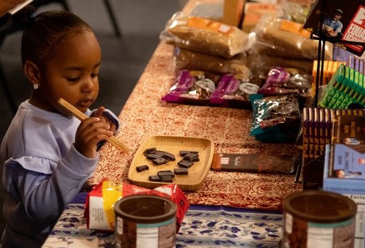 a child selects a piece of chocolate from a tray using tongs