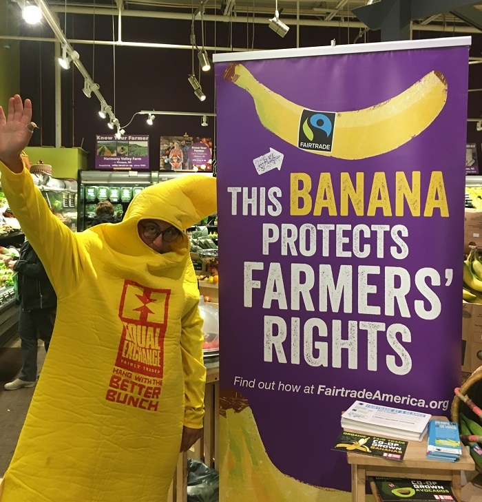 A person in a banana suit with a sign that reads "this banana protects farmers' rights"