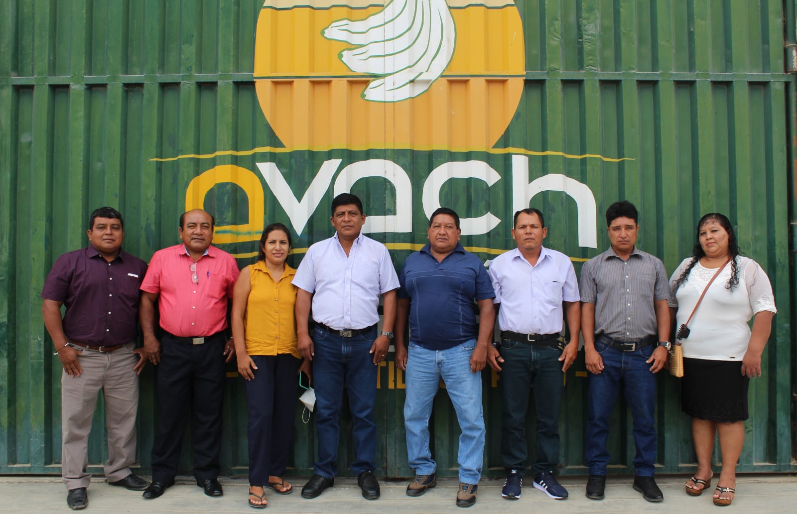 Eight directors standing in front of the AVACH warehouse