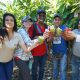 A group of smiling people hold up cacao pods