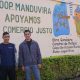 Two men stand in front of a mural at the Manduvira co-op in Paraguay
